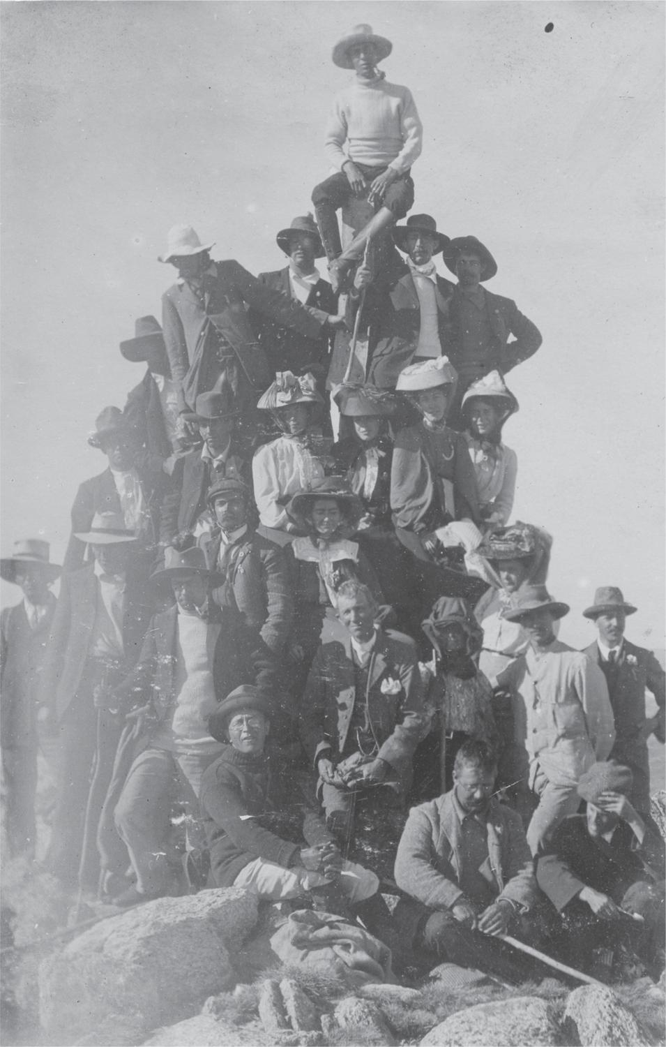 Black and white photograph of a group of men and women sitting and standing on rocks at the top of Mount Kosciuszko.