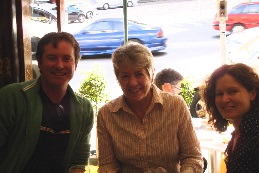 Photograph of a man and two women, seated together and smiling at the camera.