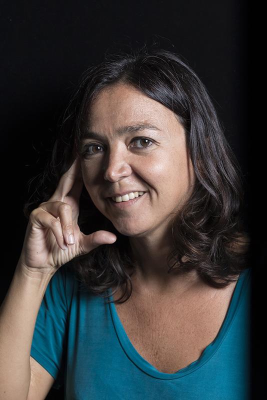 Photograph of a woman with dark hair, wearing a blue top.