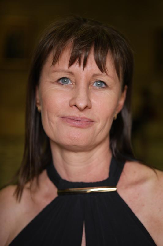 Photograph of a woman with dark hair, wearing a black halter-neck top.