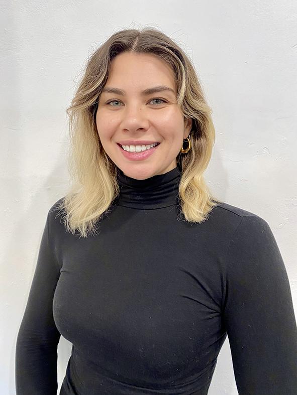 Photograph of a woman with blonde hair, wearing a black turtleneck.