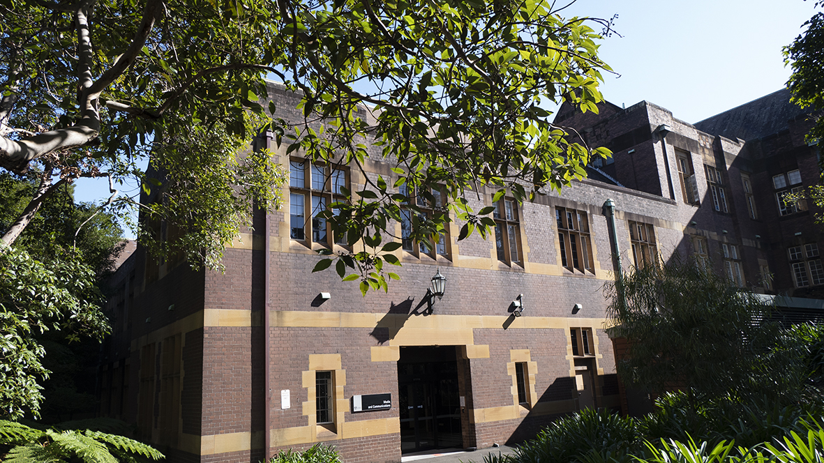 Photograph of a brown brick building with sand-coloured accents around its windows.
