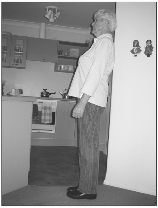 A black and white photograph of an elderly woman leaning slightly back with her heels on the ground.