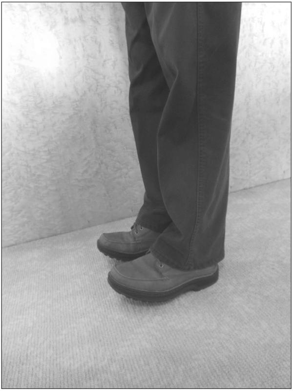 A black and white photograph of an elderly person standing on their heels.
