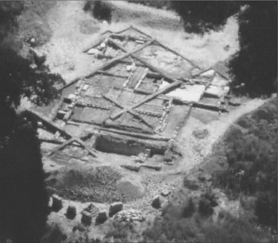 A black and white aerial photograph of the excavation. The grounds are divided into rectangles and squares with walls dividing the sections.