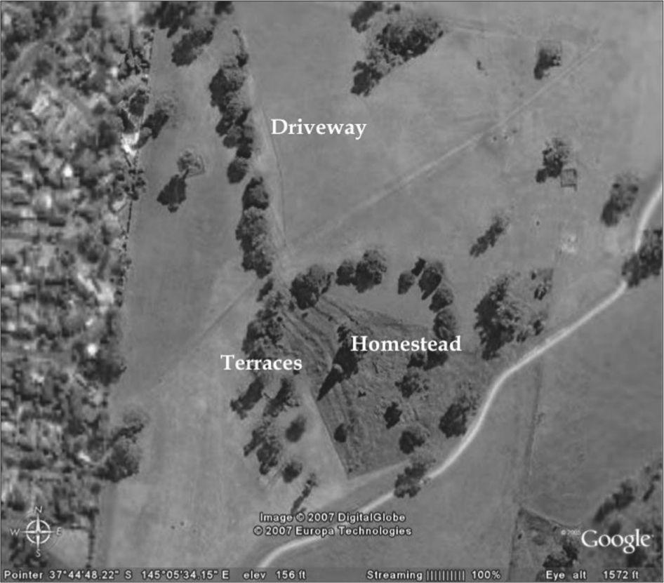 A black and white aerial photograph of the garden. It has a mostly flat lawn with a line of trees that form a circle around the terraces and homestead.