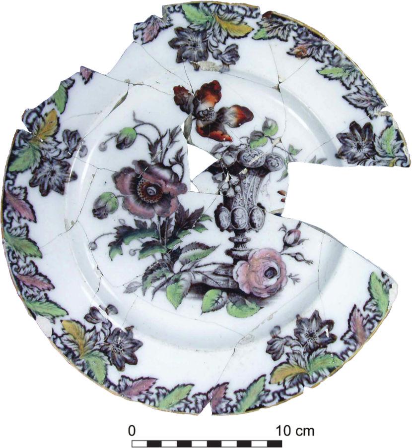 A photograph of a broken and cracked plate with green, pale pink and pale green floral patterns. 