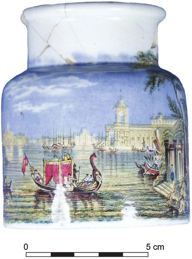 A photograph of a mustard jar with a colourful depiction of a boat carrying a red covering, approaching steps to land. Behind the boat are old buildings and an open blue sky.