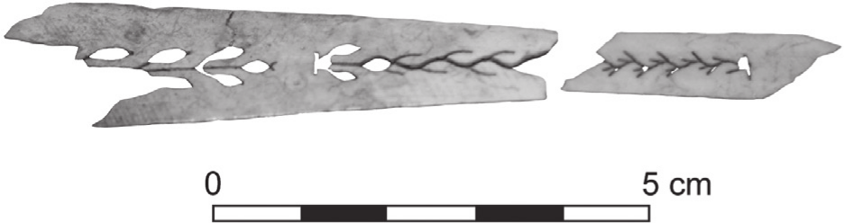 A black and white photograph of a fractured fan piece. It has a vine pattern.