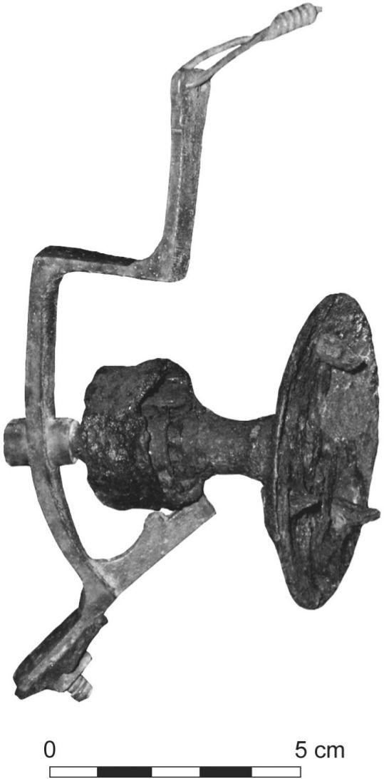 A black and white photograph of a servant bell. It is shaped almost like a clamp and the bell shell is gone revealing the inside.