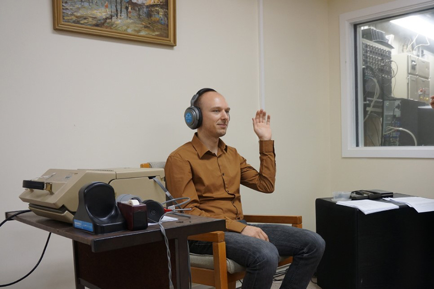 Man sitting in a listening room at the Acoustic Research Centre during a hearing screening test.