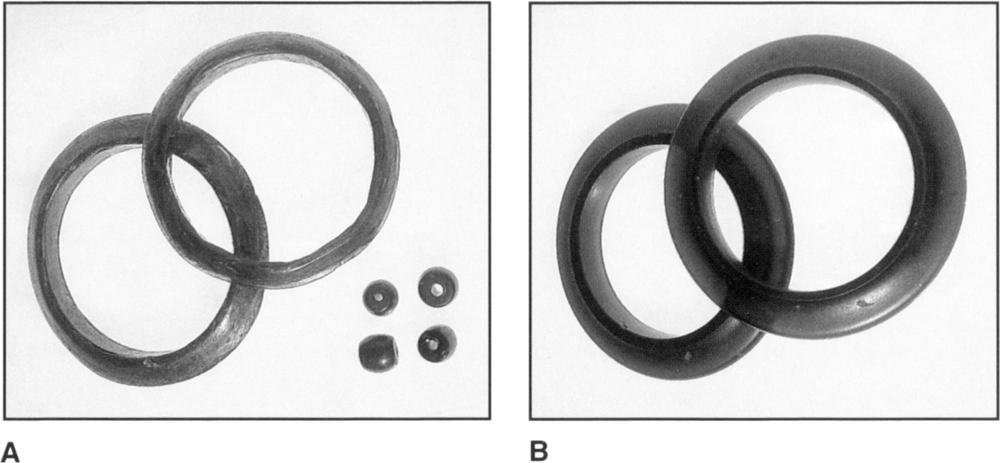 Photograph, labelled A, of two forest-green glass bracelets and three blue and obsidian-like-coloured beads. Photograph B is of replicas of the bracelets and beads made by the Dutch, which appear to be smoother and more polished and smoother in appearance, and more refined in their structure and workmanship in comparison to the the Ase jewellery which has a rustic “hand-crafted” appearance with visible line carvings on the body of the bracelets. The colours of the Dutch replica and New Guinean versions vary slightly. The bracelets from Ase has a mix of light green and subtle copper hues, while the Dutch replica has a more solid shades of green and aubergine.