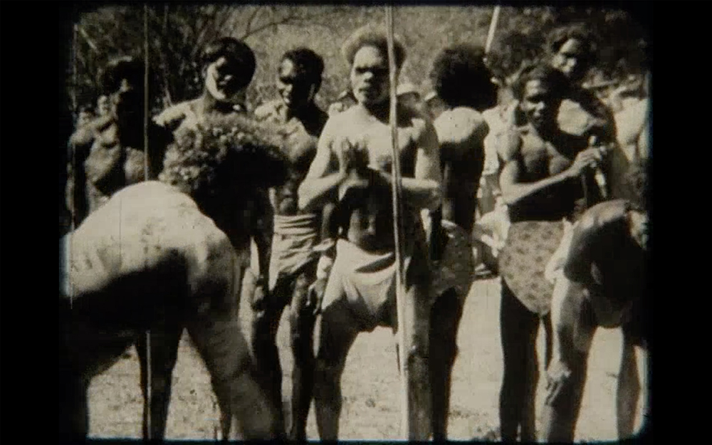 The film still shows men in the bush with body paint and spears.