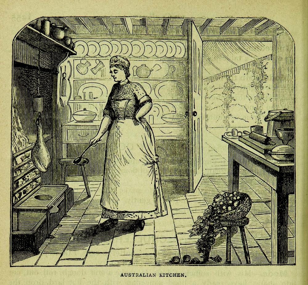 A black-and-white illustration titled "Australian Kitchen" showing a person wearing a long dress and apron standing near a brick hearth, holding a ladle over an open fire. Shelves in the background display plates, bowls, jugs and teapots, and a wooden table to the right holds various kitchenware. In the foreground, to the right, is a stool with a basket of fruit or vegetables, spilling onto the floor. An open door reveals a garden or outdoor area beyond.