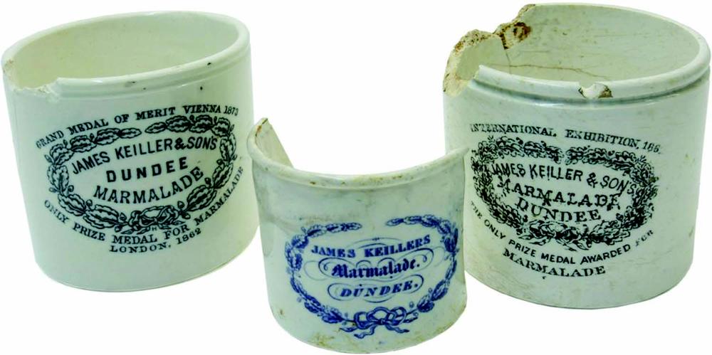 Three chipped and broken ceramic pots, isolated against a white background. Each of the pots has been printed with an ornate label with "Keller and Sons Dundee Marmalade" in the centre.
