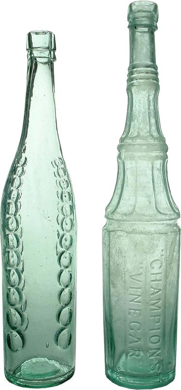 Two tall, narrow glass bottles with long necks and detailing on the sides.