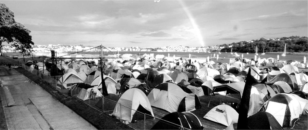 A black and white photograph of numerous tents in an area next to the waterside.