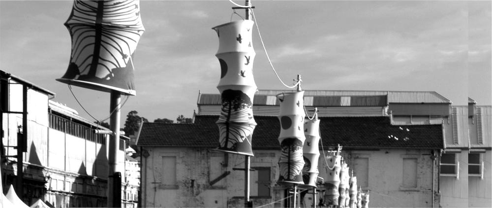 A black and white photograph of wind decorations on poles outside a large building.