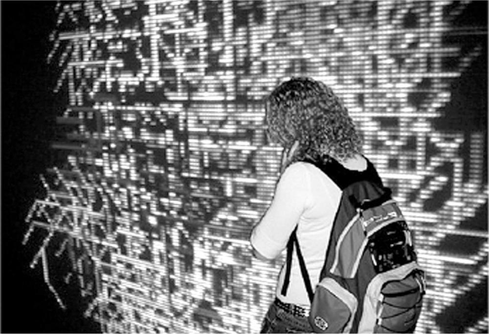 A black and white photograph of a woman with a backpack on walking in front of an ambient response visualisation.