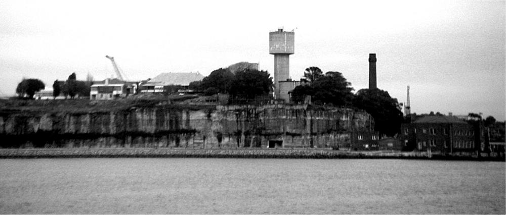 A black and white photograph of Cockatoo Island from the harbour.