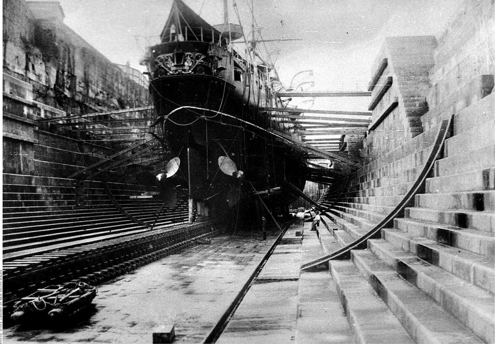 A black and white photograph of a large ship being docked on Cockatoo Island.