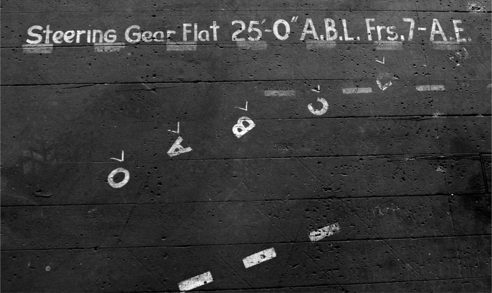 A black and white photograph of a wall with writing and ship marks on it.