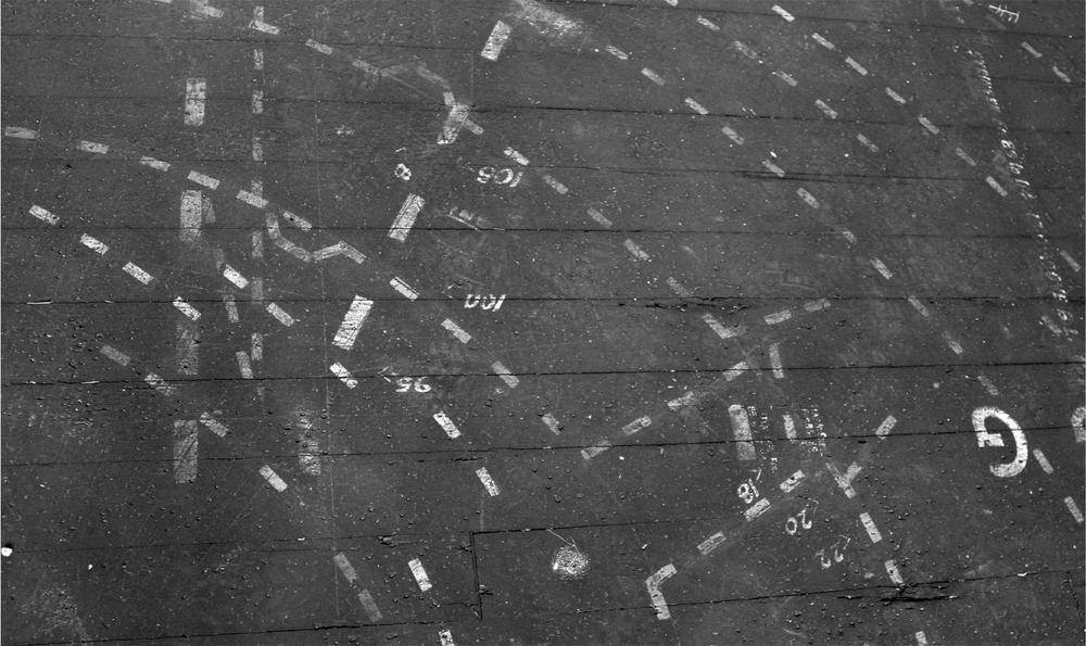 A black and white photograph of a surface with white paint marks on it.