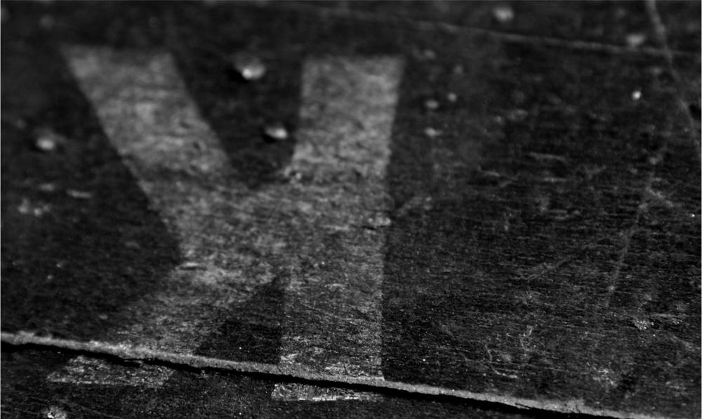 A black and white photograph of a surface with a backwards K marked.