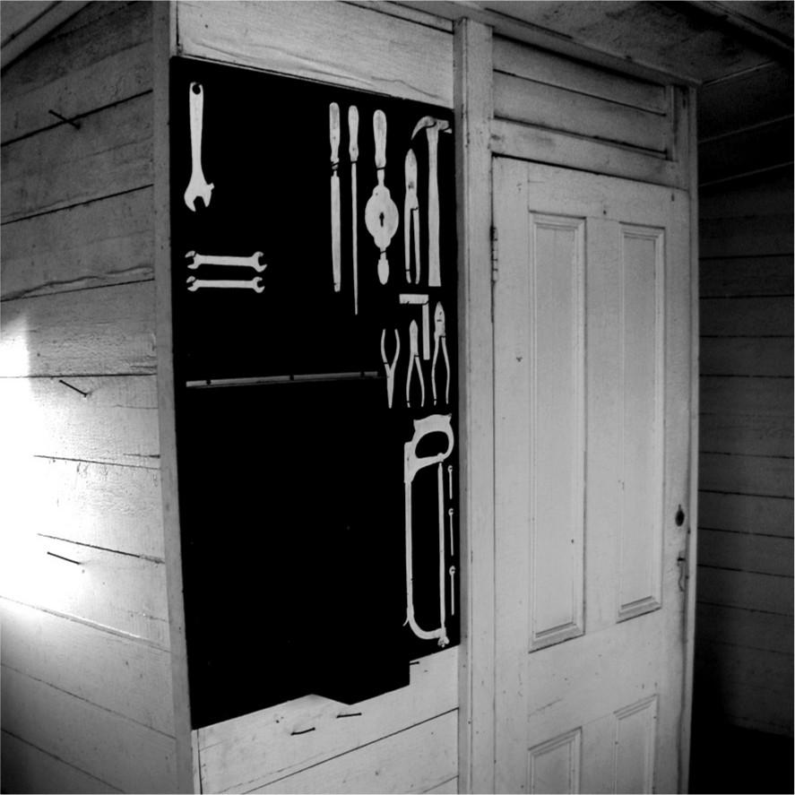 A black and white photograph of the edge of a building with a black surface and toolkit positions marked out.