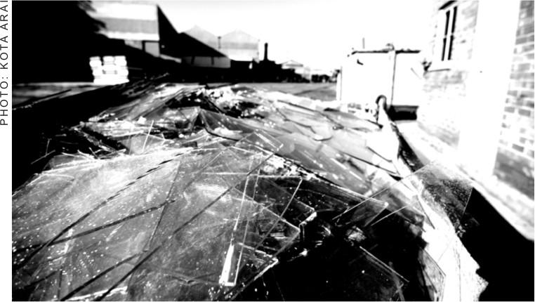 A black and white photograph of a floor with white marks all over it and buildings to the right and in the background.