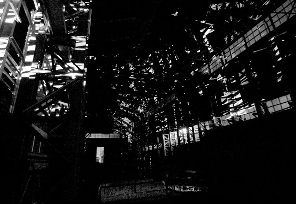 A black and white photograph of projected light beams along the walls and ceiling of the Turbine Hall.