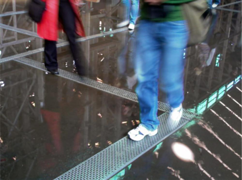 An image of people walking on beams in a room with water on the floor.
