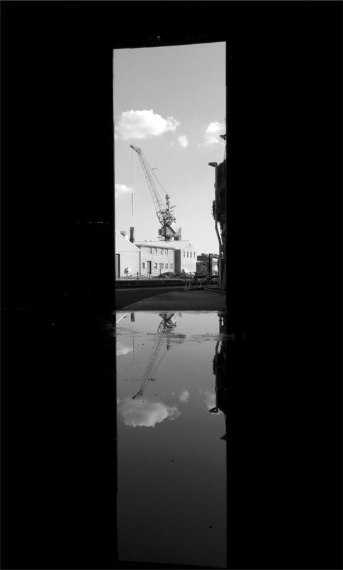 A black and white photograph of a crane seen through two panels.