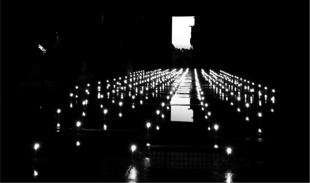 A black and white image of a light installation with lights on the floor in straight lines.