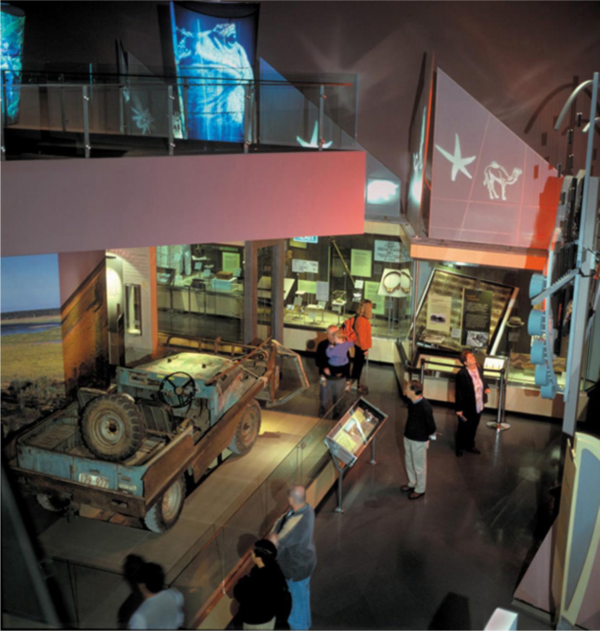 A museum with people looking at an old car model.