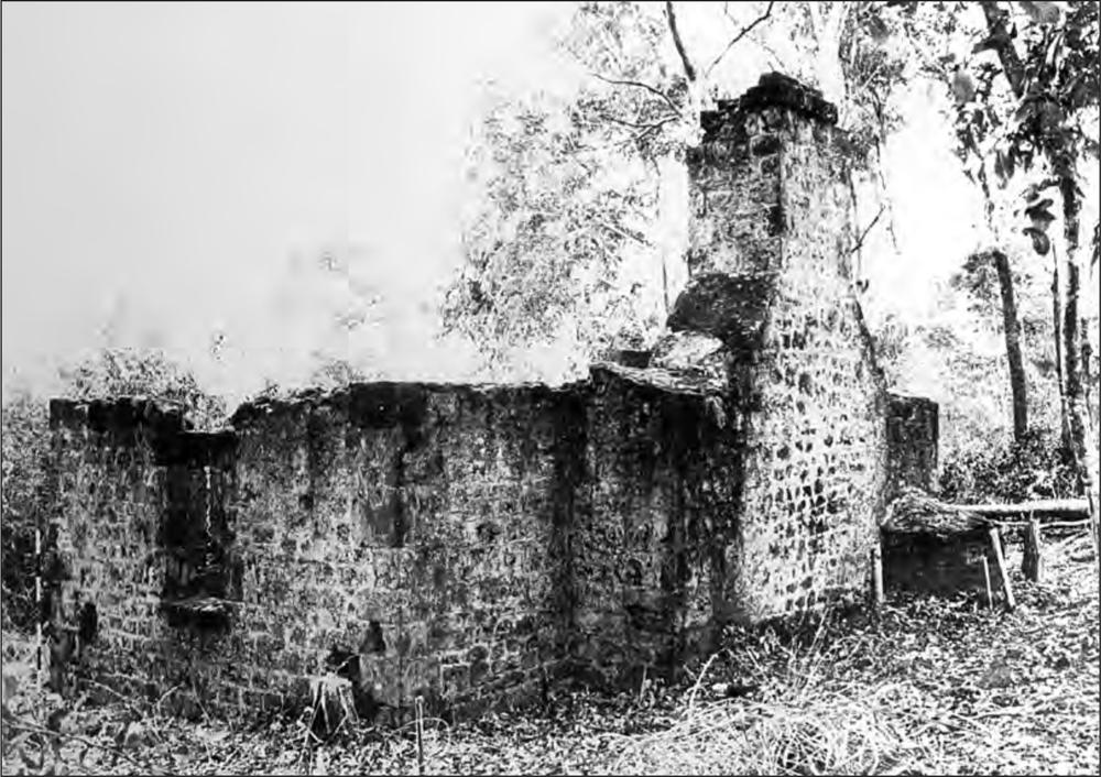 A black and white photograph of a building without a ceiling. A chimney is still standing without the tip.