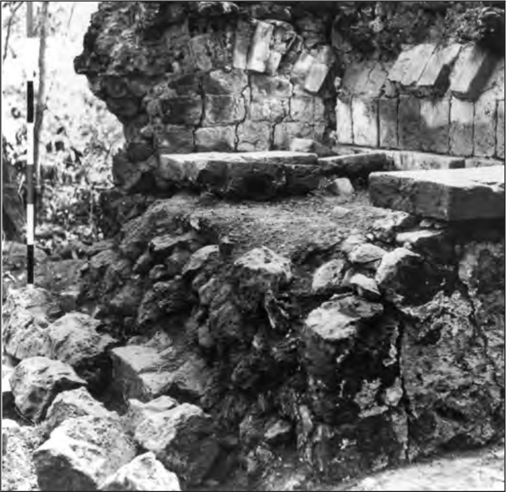 A black and white photograph of a collapsed western wall of the bakery showing solid fill construction beneath a barrel vault of masonry and brick