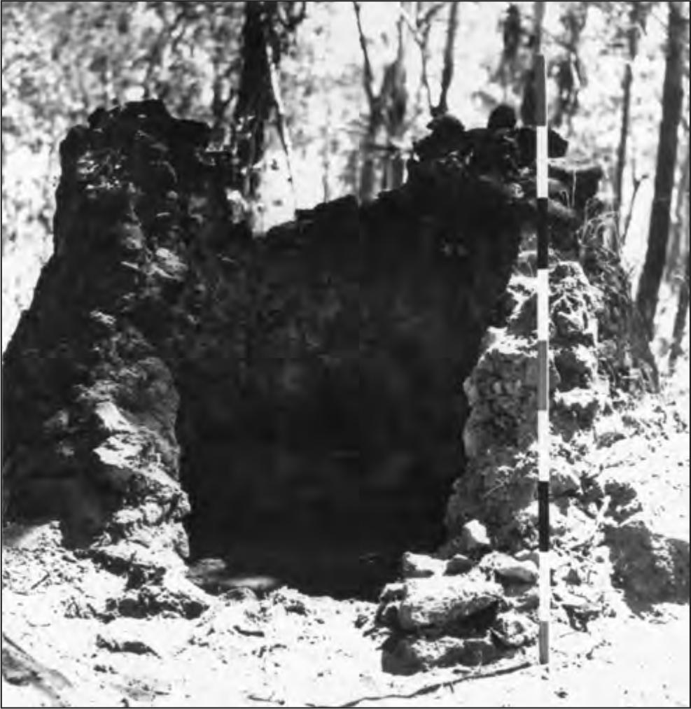 A black and white photograph of a broken kiln; it is circular but a section of it has deteriorated..