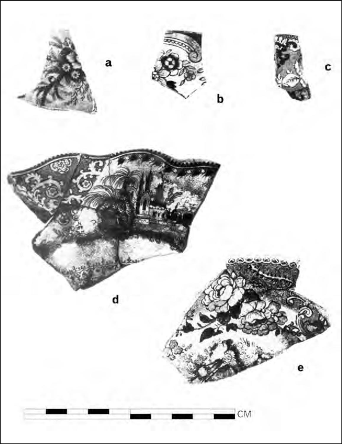 A black and white photograph of five shards of pottery. Each has a detailed pattern of blooming flowers and one has a building amidst trees printed on its rim.