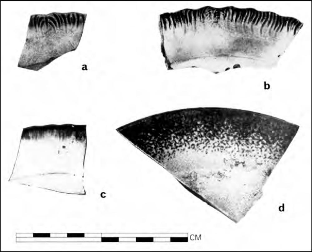 A black and white photograph of four pottery shards. Three shards have wavy dark patterns along the rim whilst the other has dotted dark patterns along the rim.