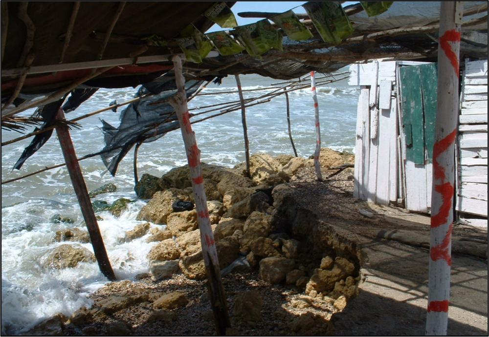 A photograph of the sea surging on the edge of a town.