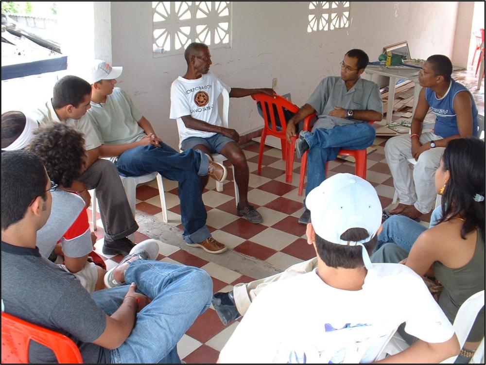 an image of men sitting around in a circle on chairs talking.