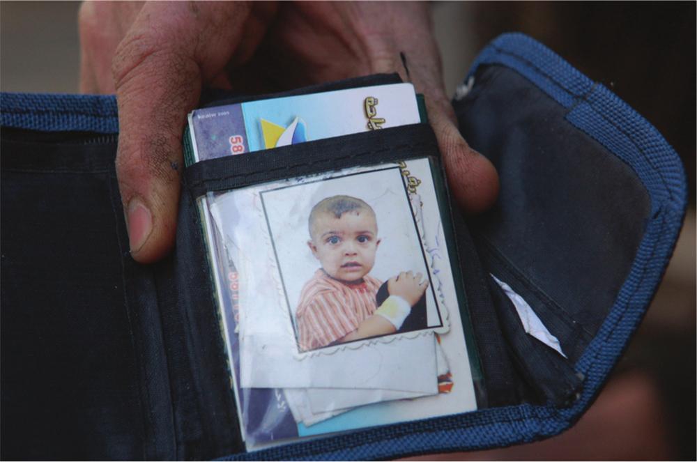 Photograph of a blue wallet containing a picture of a young boy in a red and white striped shirt.