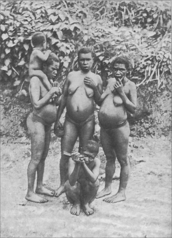 Black and white image of a group of women and children standing on the beach.