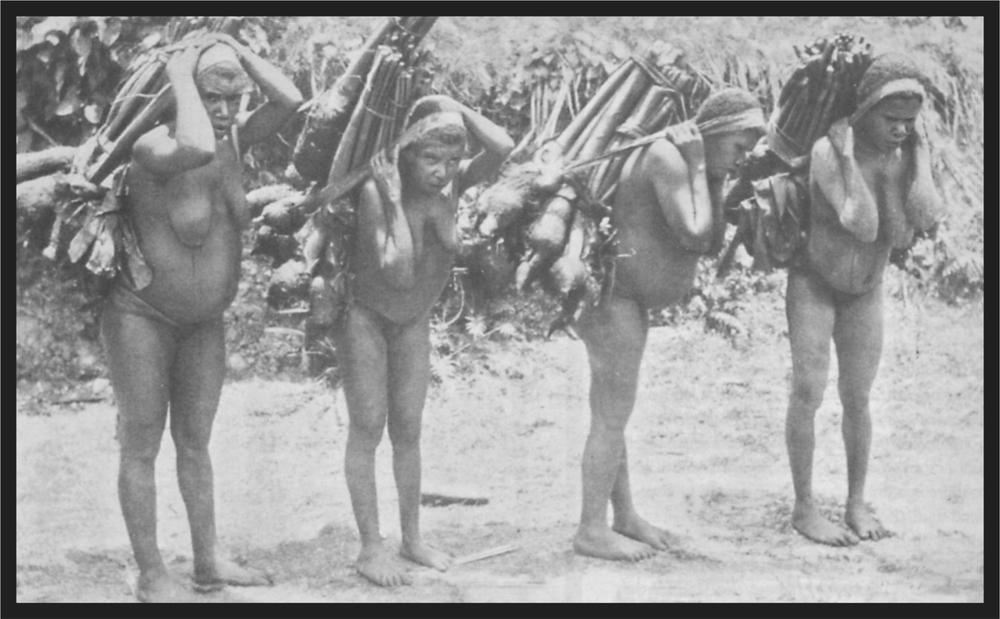 Black and white image of four women with large loads on their backs held up with material around their heads.