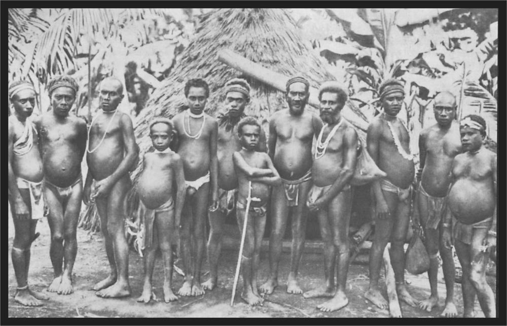 Black and white image of a group of men standing in front of a hut.