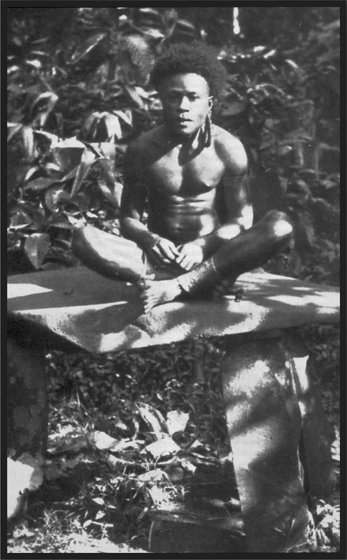 Black and white image of a young man sitting on a rock formation.