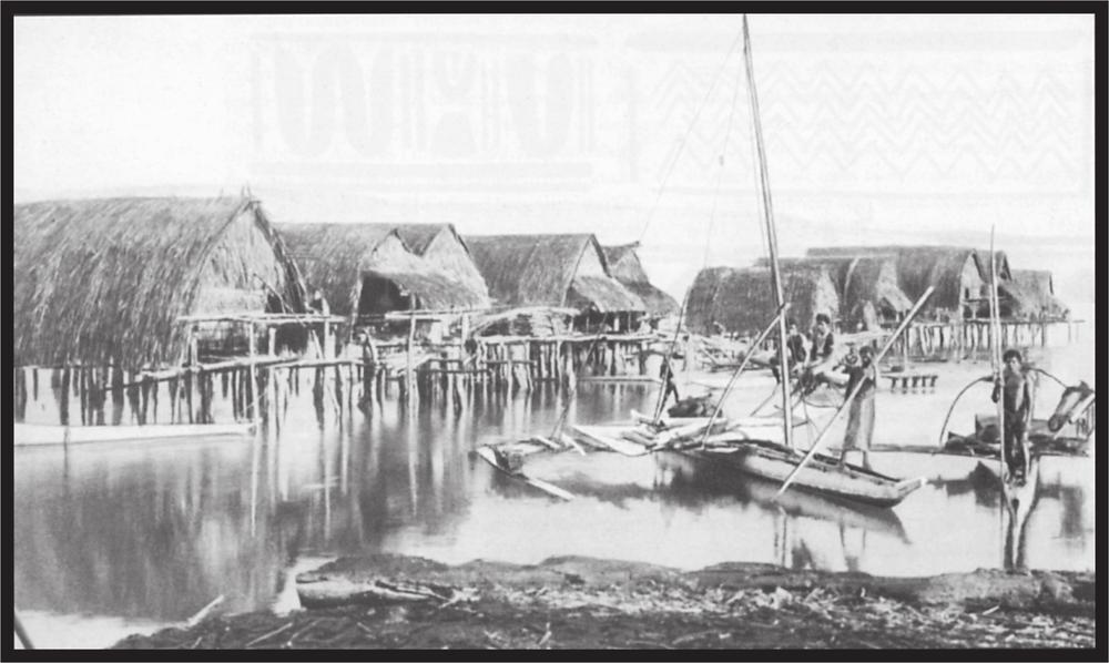 Black and white image of stilted huts in the water and people in long boats on the water.