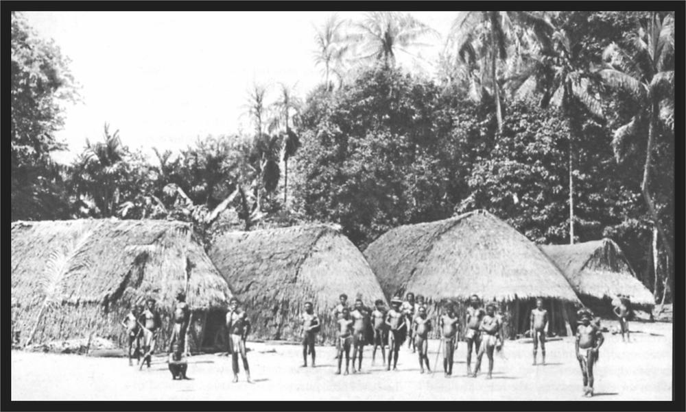 Black and white image of a group of people in their village in front of numerous huts.