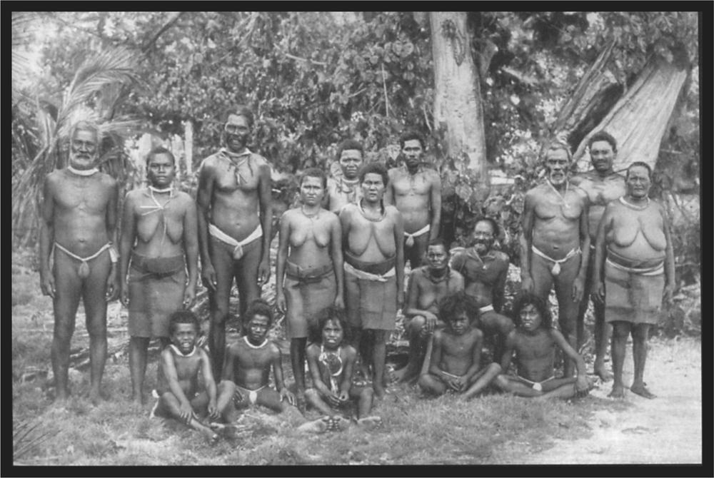 Black and white image of a group of islanders standing in their village.